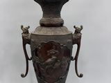 a bronze vase on a stand on a white background