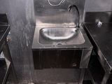 un lavabo en métal dans des toilettes publiques, avec des plans de travail noirs