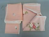 plusieurs morceaux de tissu rose ornés de fleurs brodées, posés sur une table