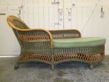 une chaise longue en osier avec un coussin vert dessus