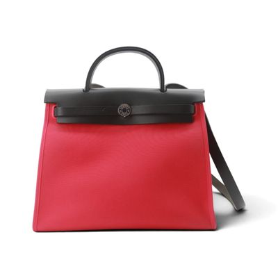 un sac à main rouge et noir posé sur une surface blanche