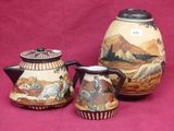 three pieces of pottery on display on a pink surface