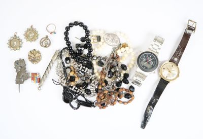 une montre, des bracelets et d'autres bijoux disposés sur une surface blanche