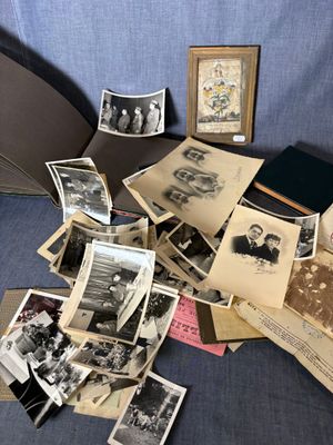 une pile de vieilles photos posée sur un lit, avec un parapluie