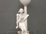 une statue blanche représentant un homme tenant une raquette de tennis