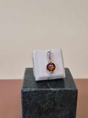 une image représentant une bague ornée d'une pierre brune posée sur un bloc de marbre