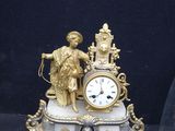 a gold clock sitting on a marble base with a statue on top of it