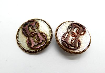 Paire de boutons en métal gris sertis de nacre, monogrammés …