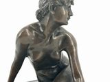 a bronze statue of a woman sitting on a rock