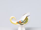 petit oiseau en céramique au bec jaune, perché sur un vase blanc