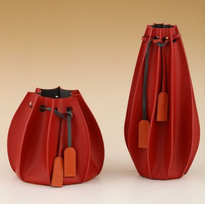 une paire de vases en cuir rouge ornés d'étiquettes, sur fond beige