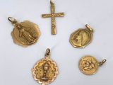 a group of gold religious charms including a cross, a medal, and a medal