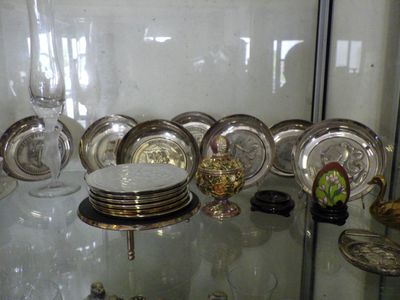 a glass display case with a lot of silver plates on it