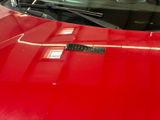 a close up of a red car with a sticker on it ' s hood