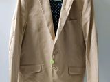 beige jacket hanging on a hanger on a wall with a polka dot shirt underneath it