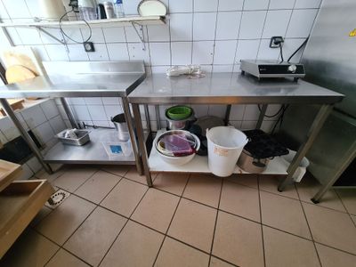 a kitchen with a stainless steel counter top and two buckets on the floor
