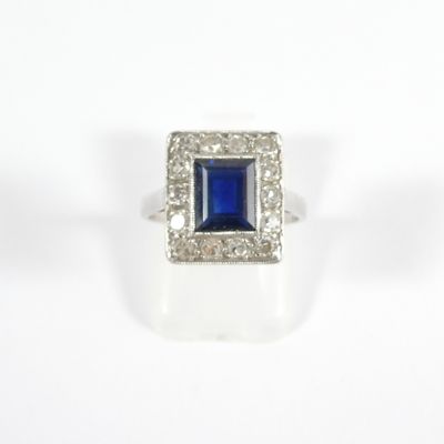 a close up of a ring with a blue stone surrounded by diamonds