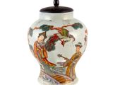 un vase blanc décoré d'une peinture et muni d'un couvercle noir