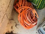 an orange hose sitting on the floor next to a green bag