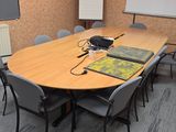 des tables et des chaises dans une salle de conférence équipée d'un projecteur et d'un écran de projection