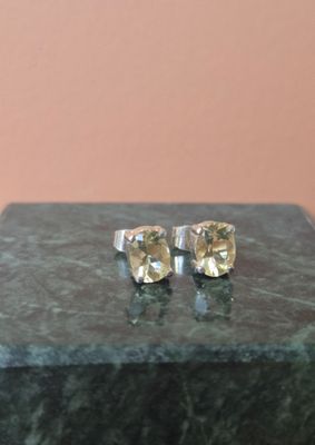 une paire de boucles d'oreilles à clous en saphir jaune posées sur un bloc de marbre