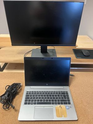 un ordinateur portable ouvert posé sur un bureau en bois, à côté d'un écran