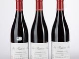trois bouteilles de vin rouge posées sur une table blanche