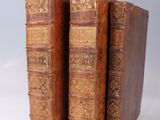 two old books sitting on top of each other on a white surface