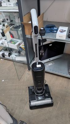 a vacuum that is sitting on the floor next to a shelf