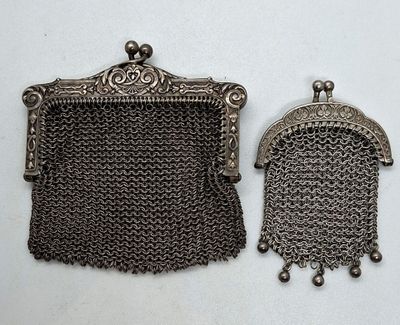 deux porte-monnaie en métal argenté et un porte-monnaie en cotte de mailles posés sur une surface blanche