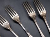 five forks and spoons are lined up on a black surface