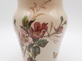 un vase sur lequel sont peintes des fleurs, sur un fond blanc