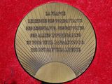 a plaque on a red surface with a black ribbon