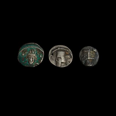 trois pièces anciennes, argentées et vertes, sur fond noir