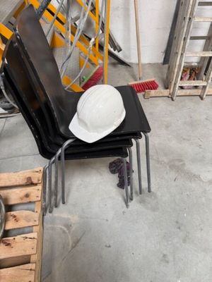 un chapeau blanc posé sur une chaise noire dans une pièce
