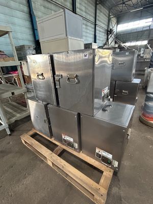 Plusieurs appareils électroménagers en acier inoxydable sont empilés sur des palettes dans un entrepôt