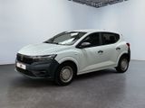 La voiture blanche est garée dans une grande pièce aux murs blancs.