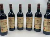 six bottles of red wine lined up in a row on a table