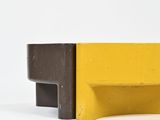 yellow and black bench against a white wall on a white background