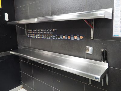 une photo d'une étagère en acier inoxydable dans des toilettes publiques