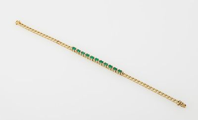 a gold bracelet with emerald stones on a white background