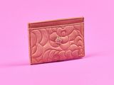 un porte-cartes rose posé sur une surface rose