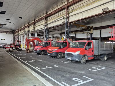 several red trucks are parked in a garage with a man on a lift