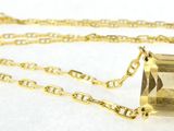 a close up of a necklace on a white surface with a gold chain