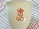 une tasse blanche ornée d'une couronne dorée