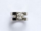 une photo d'une bague en diamant posée sur une surface blanche