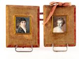 une paire de portraits encadrés représentant une femme et un homme, ornés d'un ruban rouge