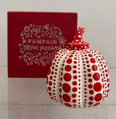 a red and white ornament on a table next to a red box