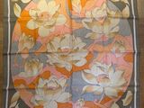 une photo d'un foulard carré orné de fleurs, posé sur un parquet