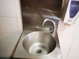 un évier en acier inoxydable dans le coin d'une toilette publique